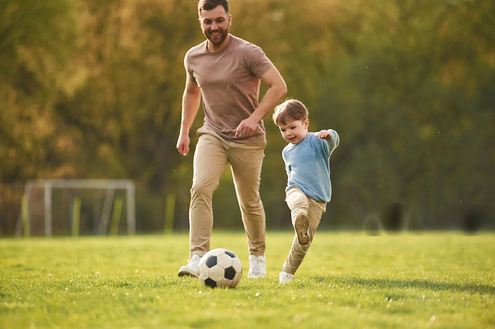 Padre e hijo jugando al fútbol en el césped
